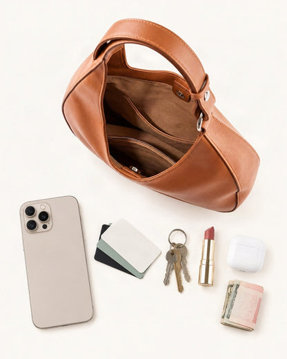What fits in the Split Leather Crescent Shoulder Bag: smartphone up to 6.9 in, cards, keys, a lipstick, airpods in their case, a few banknotes folded over into a small stack, no complete flat bill face showing