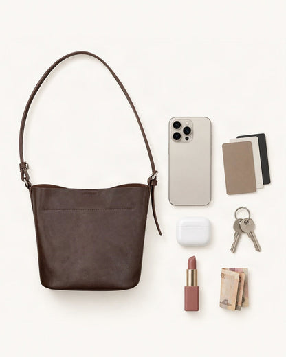 What fits in the Top-Grain Cowhide Mini Bucket Shoulder Bag: smartphone up to 6.9 in, cards, keys, a lipstick, airpods in their case, a few banknotes folded over into a small stack, no complete flat bill face showing