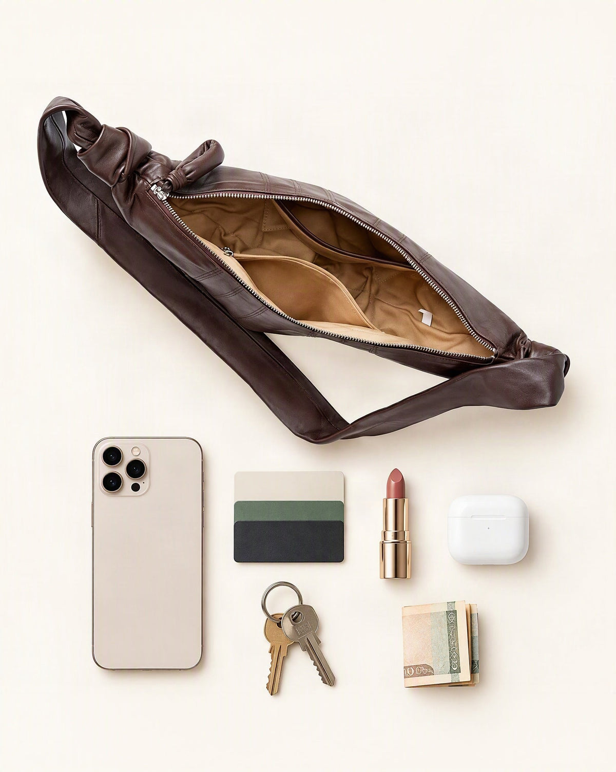 What fits in the Lambskin Crescent Crossbody Bag with Knotted Strap: smartphone up to 6.9 in, cards, keys, a lipstick, airpods in their case, a few banknotes folded over into a small stack, no complete flat bill face showing
